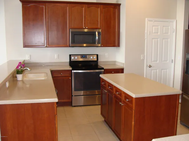 a kitchen with stainless steel appliances a stove a microwave a sink a refrigerator and cabinets