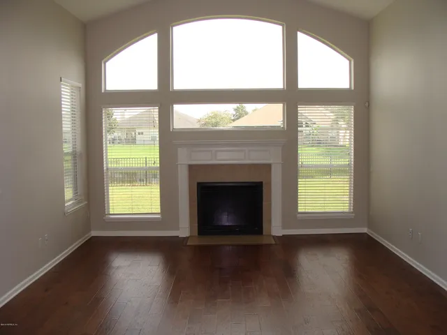 an empty room with wooden floor and a fireplace