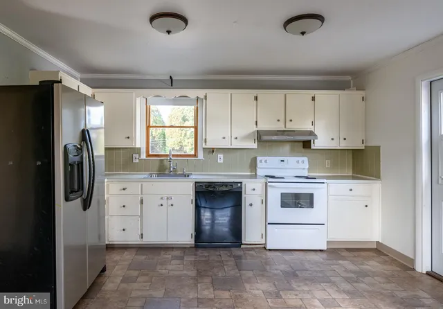 a kitchen with granite countertop a refrigerator stove and white cabinets