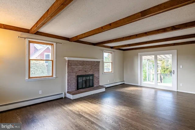 an empty room with wooden floor fireplace and windows