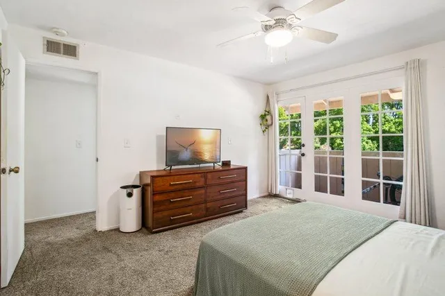 a bedroom with a bed and a flat tv screen on dresser