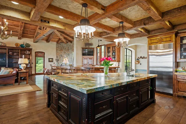 a dining room with wooden floor a chandelier a glass table and chairs