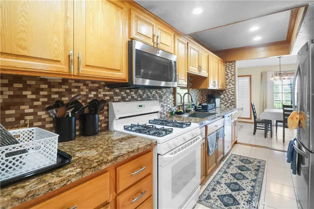 a kitchen with granite countertop kitchen island stainless steel appliances a sink stove and cabinets