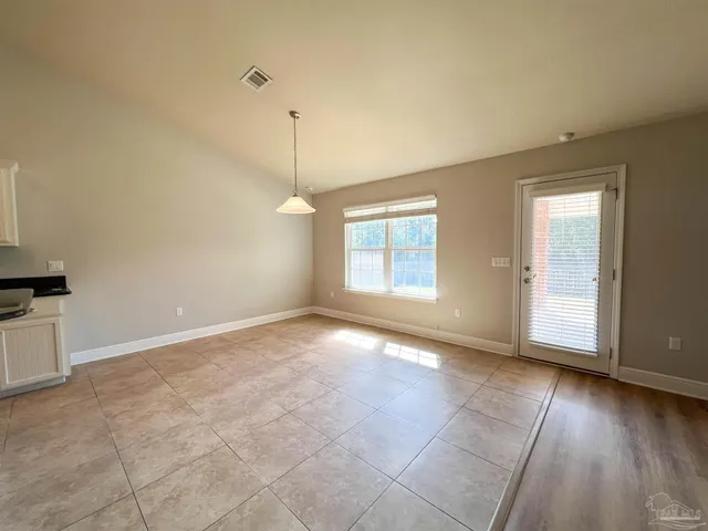 an empty room with wooden floor cabinet and windows