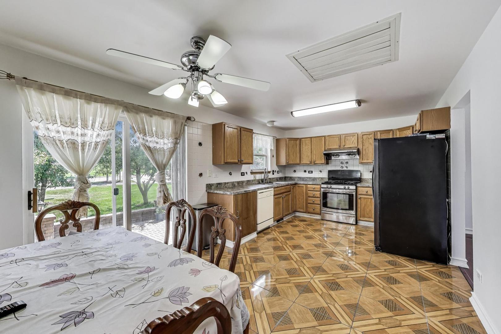 487 Anna Lane Romeoville, IL 60446 - Photo 8 of 38 a kitchen with stainless steel appliances kitchen island granite countertop a refrigerator a stove a sink a dining table and chairs with wooden floor