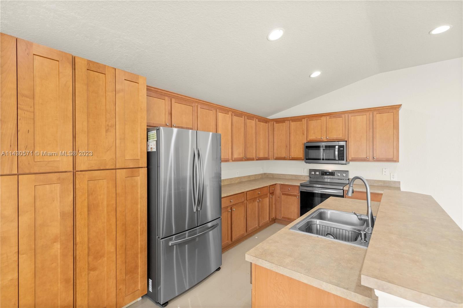 5453 Southwest 40th Street Ocala, FL 34474 - Photo 8 of 40 a kitchen with stainless steel appliances granite countertop a refrigerator a stove a sink and a refrigerator with wooden cabinets