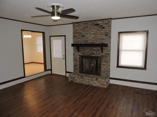 an empty room with wooden floor a fireplace and windows