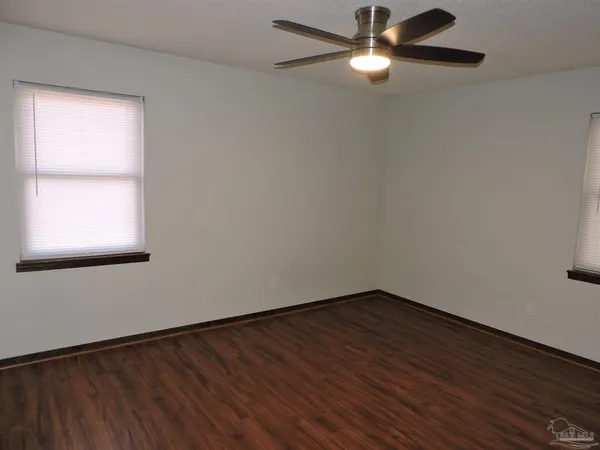 a view of empty room with wooden floor and fan