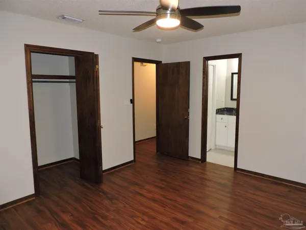 an empty room with wooden floor and a ceiling fan