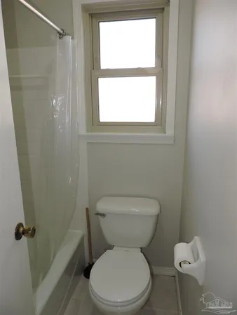 a white toilet sitting next to a window in a bathroom
