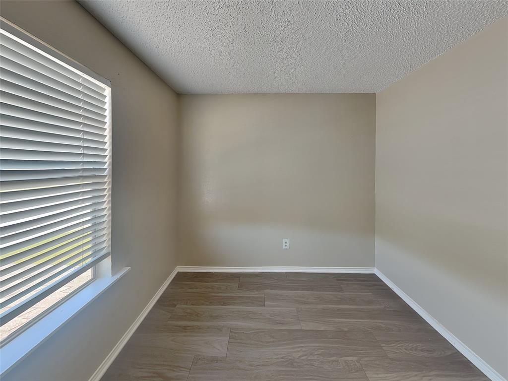 852 Northwest Summercrest Boulevard, Unit B Burleson, TX 76028 - Photo 8 of 13 a view of an empty room with wooden floor and a window