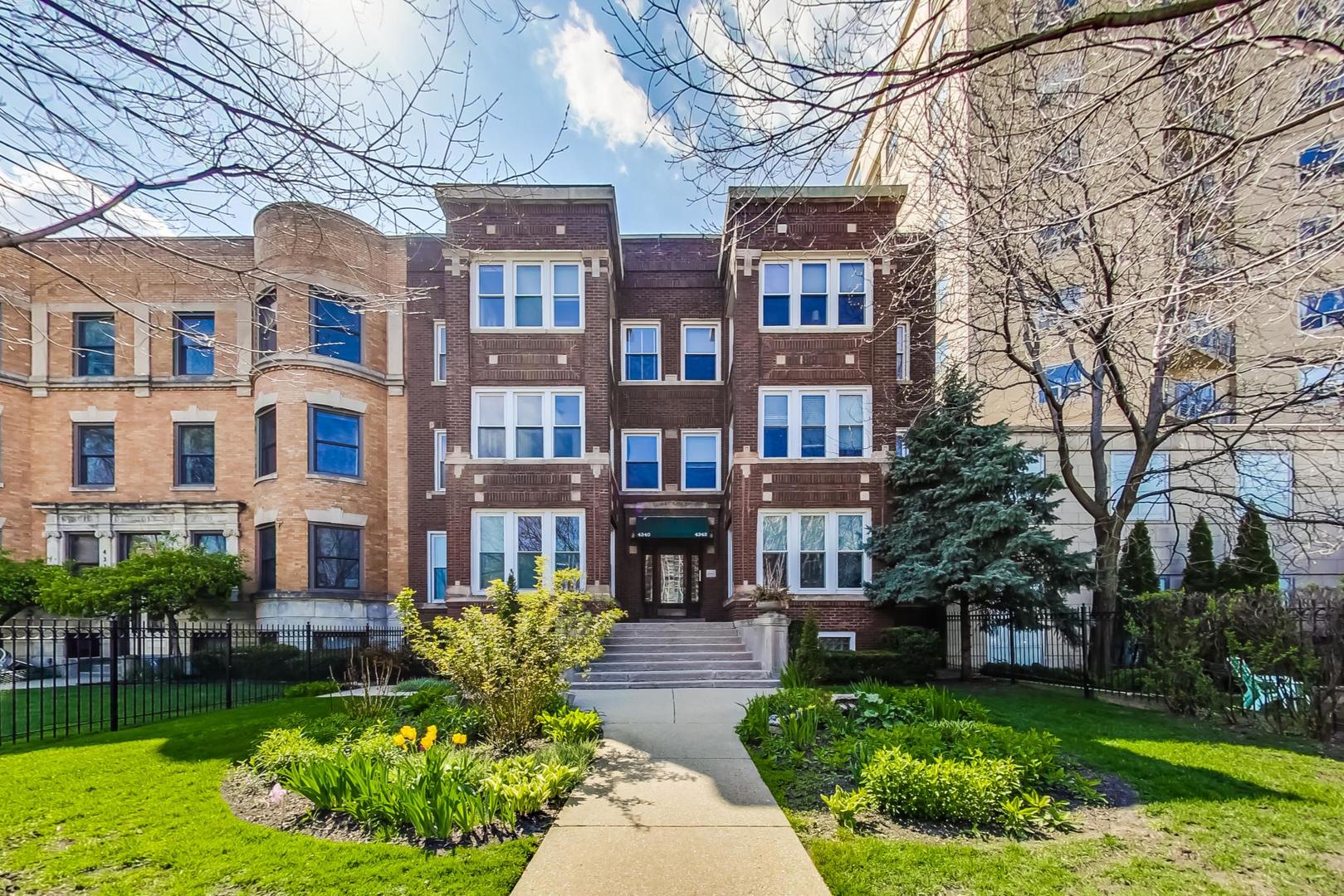 a front view of a residential apartment building with a yard and potted plants