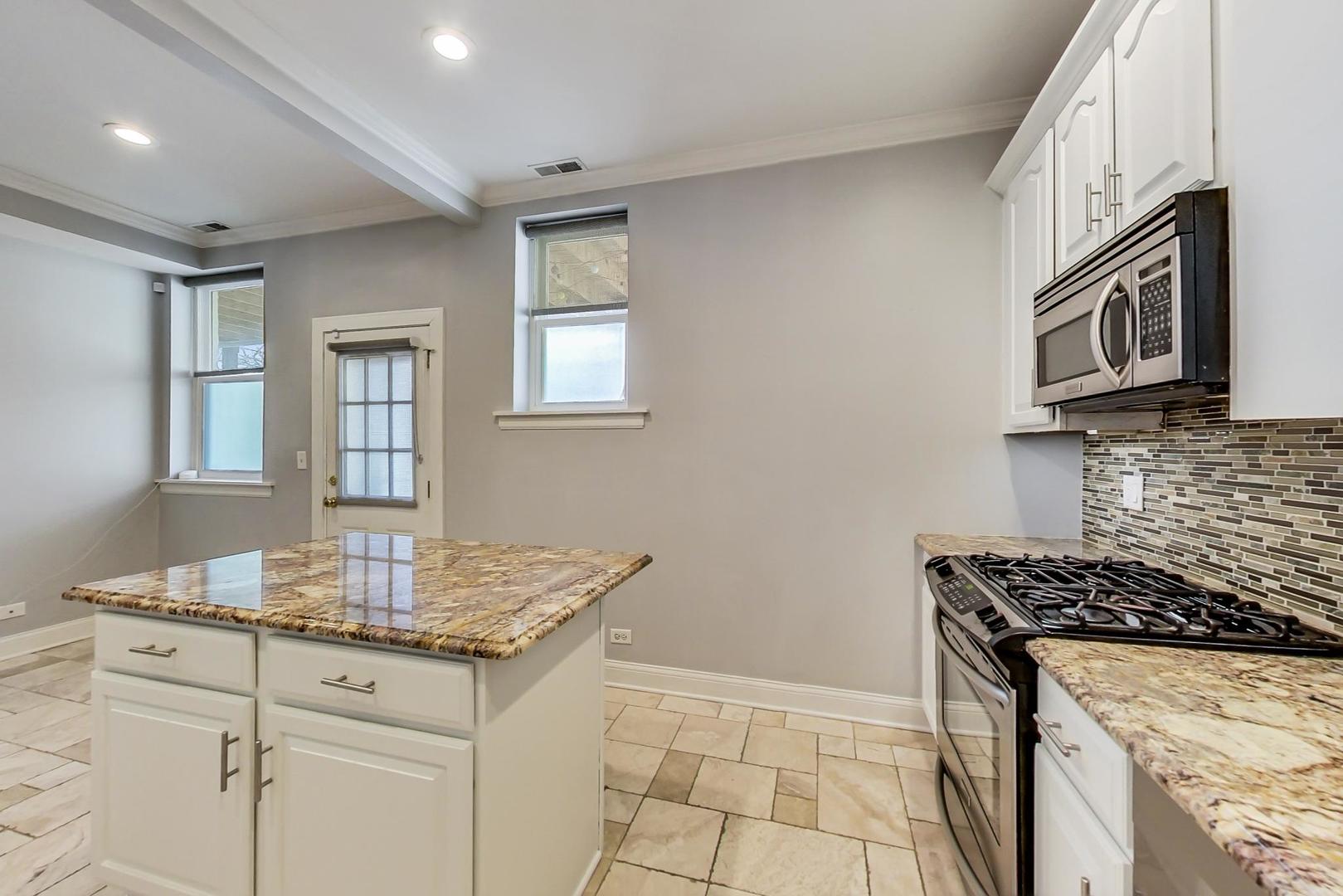 4342 North Sheridan Road, Unit 1N Chicago, IL 60613 - Photo 14 of 29 a kitchen with granite countertop a stove sink and microwave