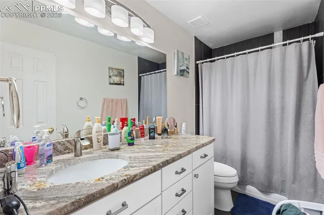 a bathroom with a granite countertop sink a toilet and a mirror