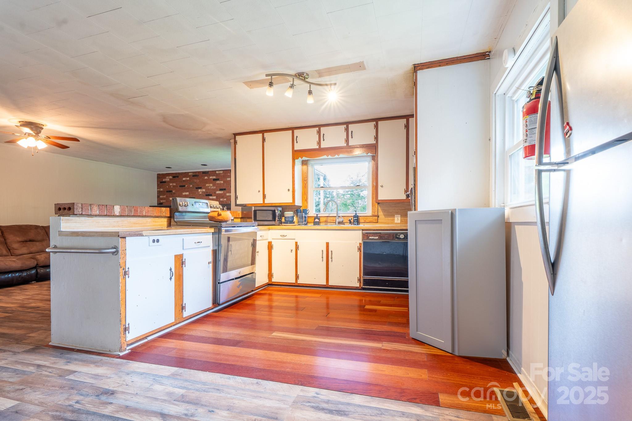 1851 Enon Road Valdese, NC 28690 - Photo 10 of 30 a kitchen with stainless steel appliances granite countertop a refrigerator a sink dishwasher and white cabinets with wooden floor