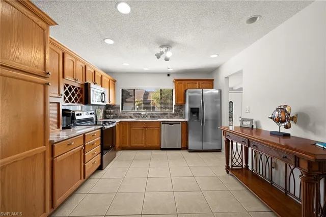 a kitchen with stainless steel appliances granite countertop a stove top oven a sink dishwasher and a refrigerator