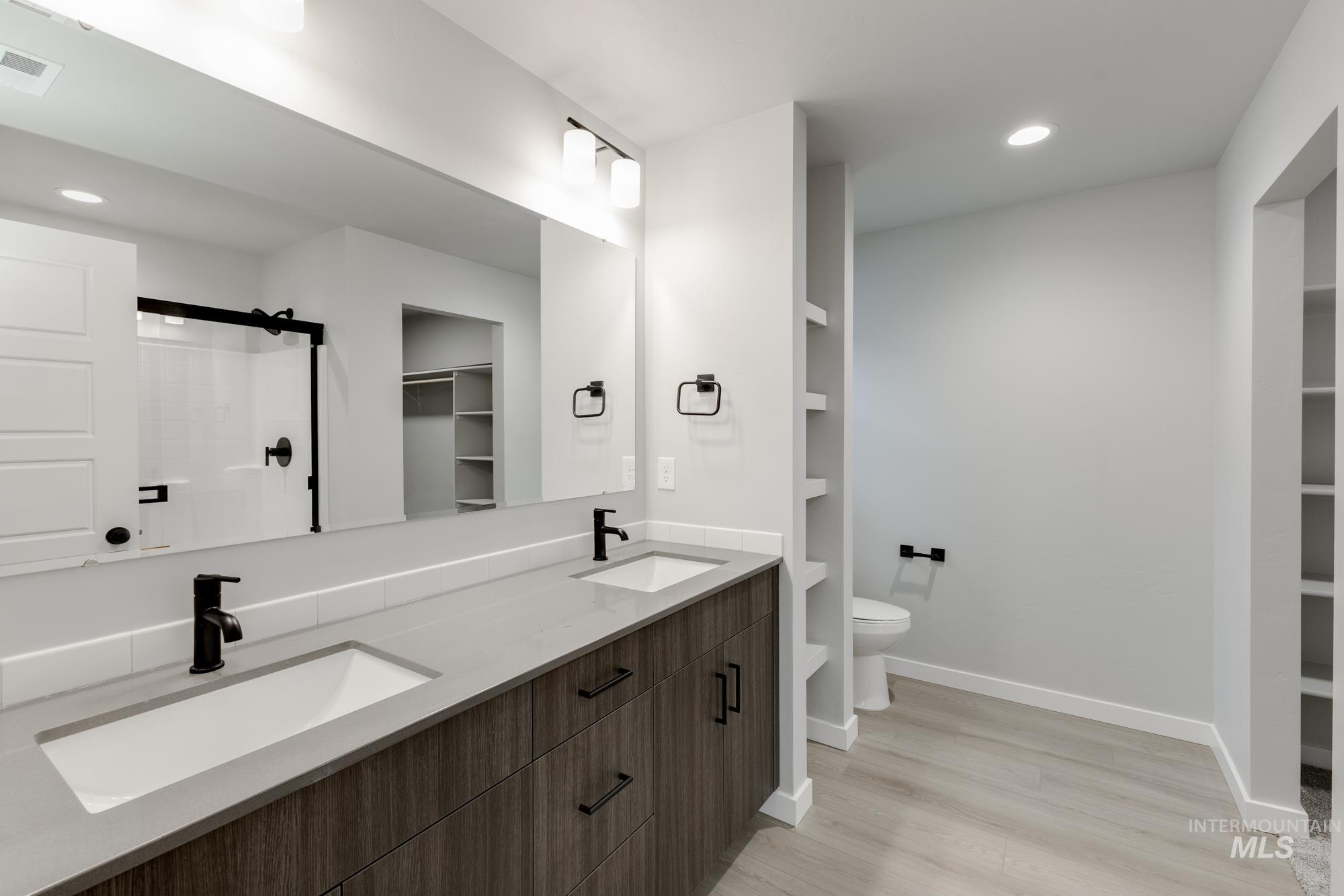 869 North Aleppo Way Meridian, ID 83642 - Photo 21 of 22 Bathroom featuring a walk in closet, double vanity, a shower stall, recessed lighting, and light wood-style floors
