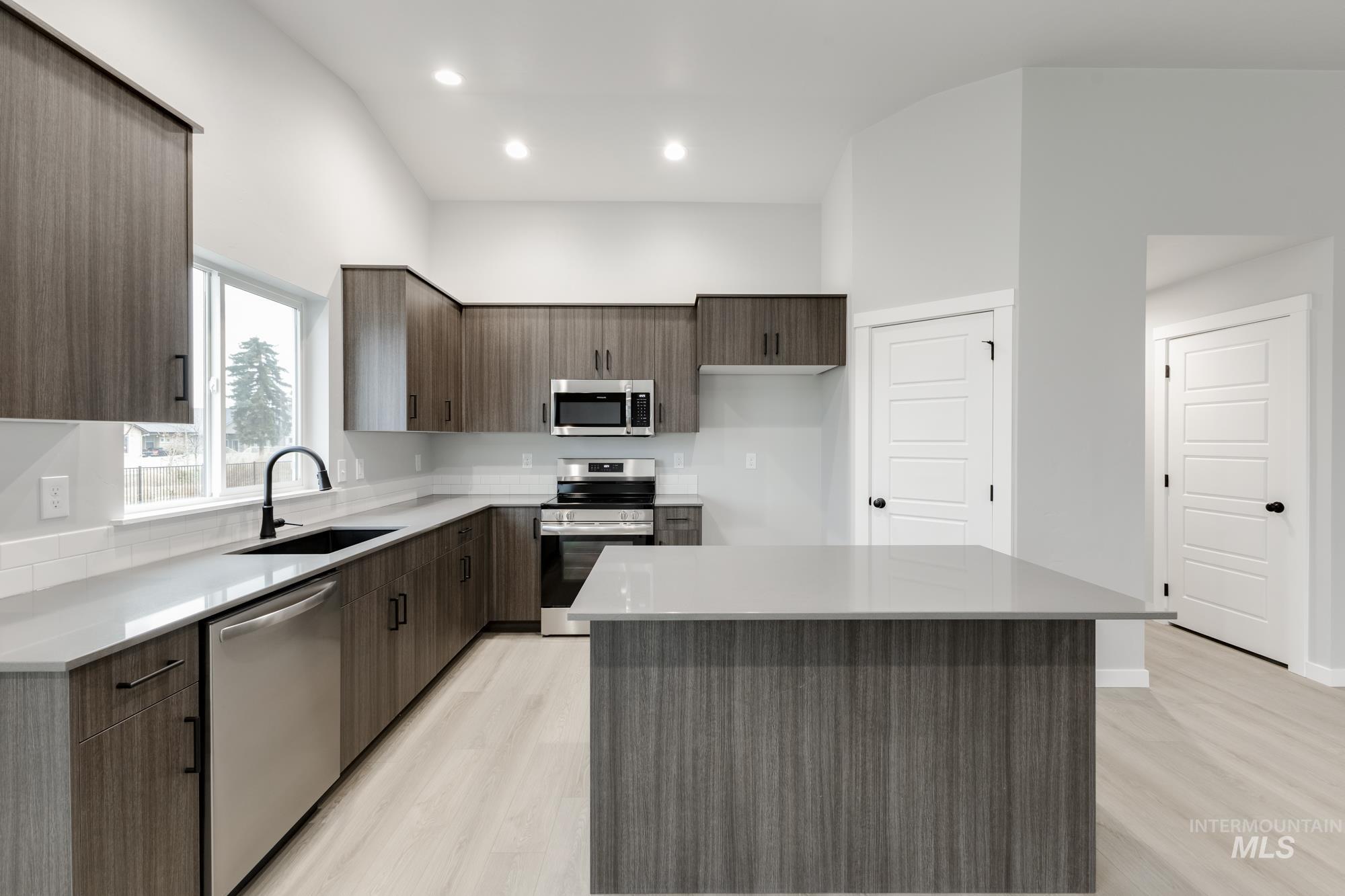 869 North Aleppo Way Meridian, ID 83642 - Photo 4 of 22 Kitchen with modern cabinets, stainless steel appliances, a center island, light wood-style flooring, and light stone countertops