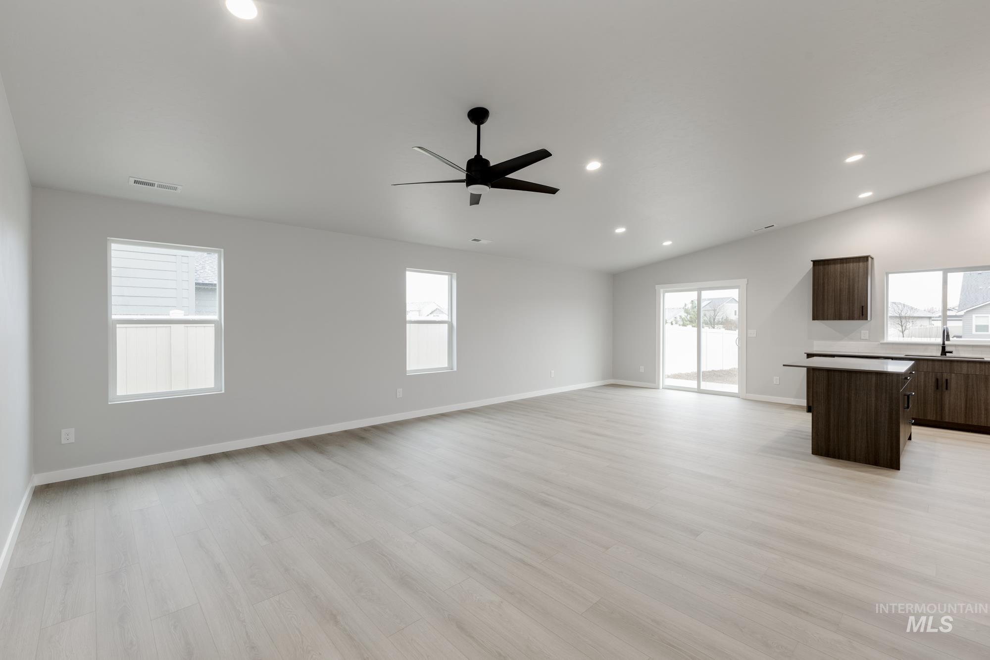 869 North Aleppo Way Meridian, ID 83642 - Photo 6 of 22 Unfurnished living room with recessed lighting, light wood-style flooring, lofted ceiling, healthy amount of natural light, and a ceiling fan