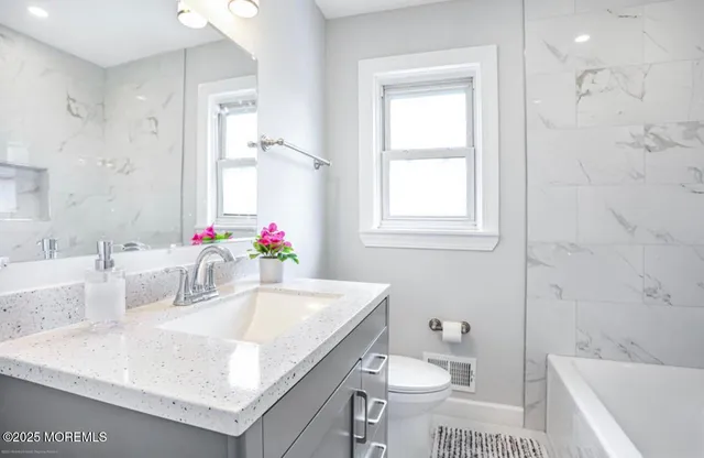 a bathroom with a granite countertop sink a toilet and shower