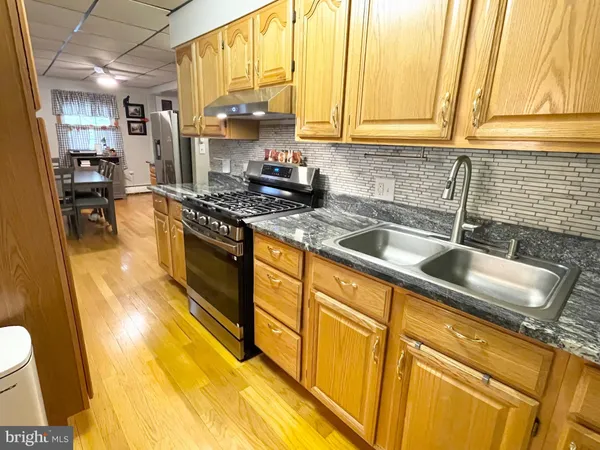 a kitchen with stainless steel appliances granite countertop a sink a stove and a wooden cabinets