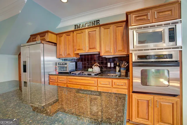 a kitchen with stainless steel appliances kitchen island granite countertop a refrigerator a stove top oven a sink and dishwasher