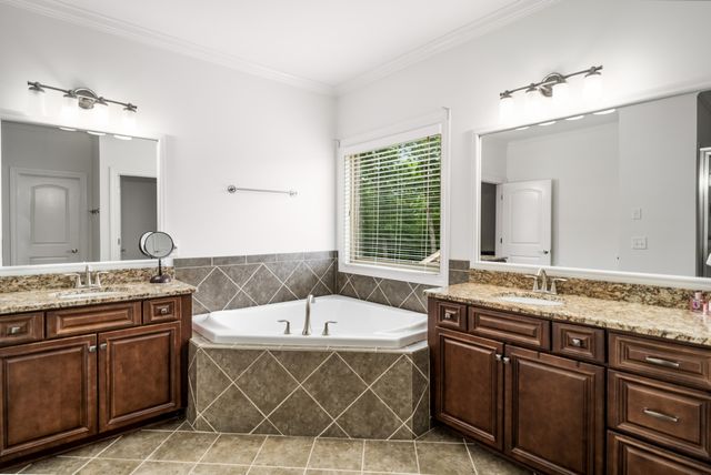 a bathroom with a tub a sink double vanity and a mirror