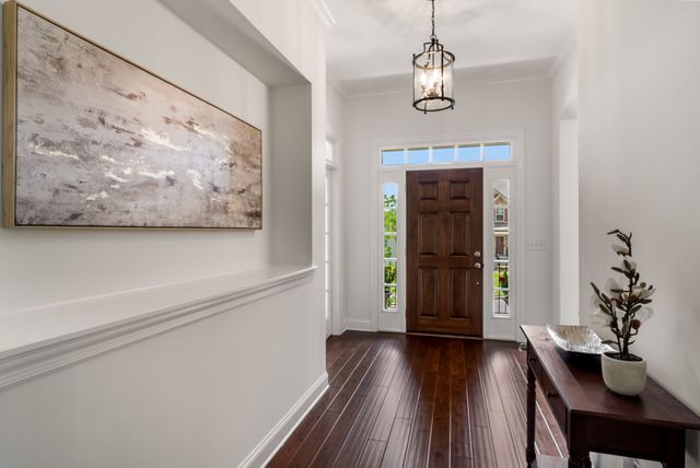 a view of a hallway with wooden floor and a chandelier
