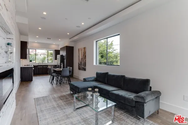 a kitchen with stainless steel appliances kitchen island granite countertop a refrigerator a sink a stove a dining table and chairs