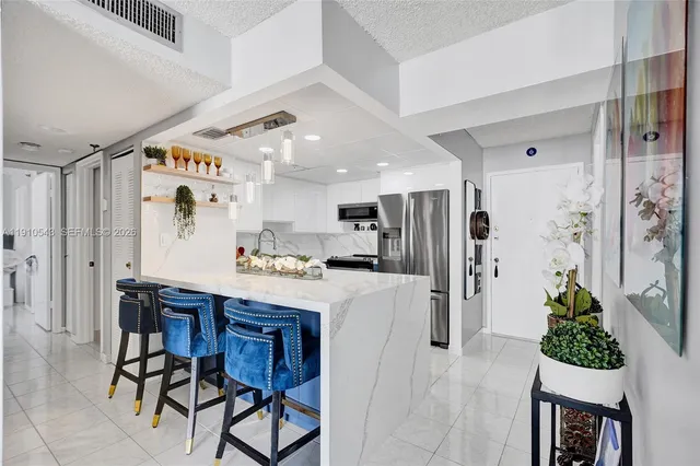 a kitchen with stainless steel appliances kitchen island granite countertop a refrigerator and a dining table