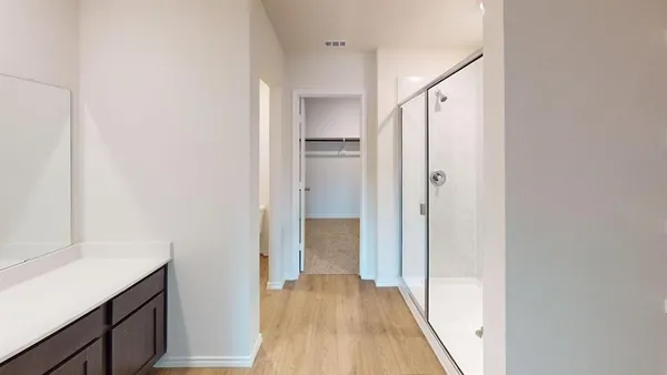 a view of a hallway with wooden floor and a bathroom
