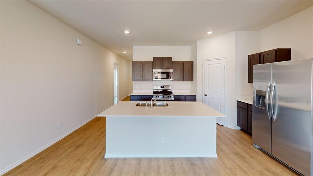 4124 Turquoise Avenue Celina, TX 75009 - Photo 5 of 17 a view of a kitchen with kitchen island a sink wooden floor and stainless steel appliances