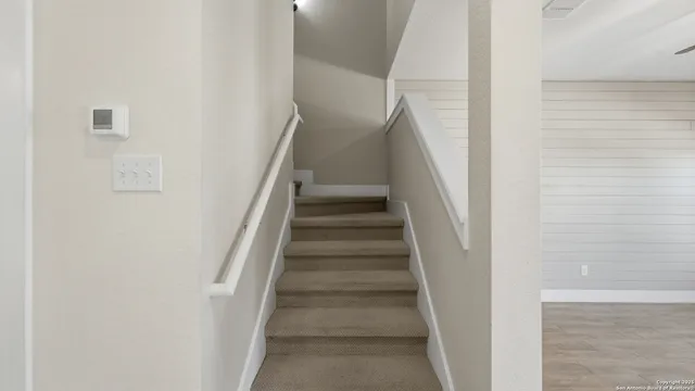 a view of staircase with white walls and white door