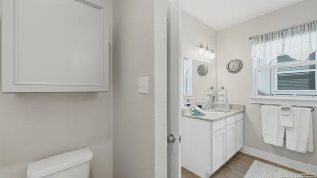 a bathroom with a granite countertop sink a toilet and a mirror
