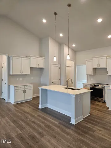 a large kitchen with kitchen island a stove a sink a center island and wooden floor