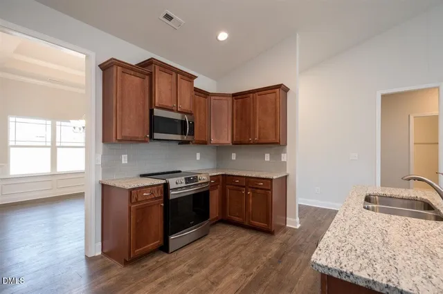 a kitchen with stainless steel appliances granite countertop a stove a sink dishwasher and a microwave oven with wooden floor