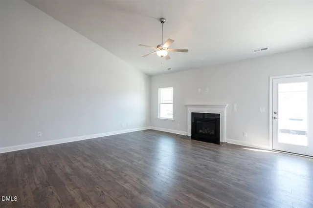 an empty room with wooden floor fireplace and windows