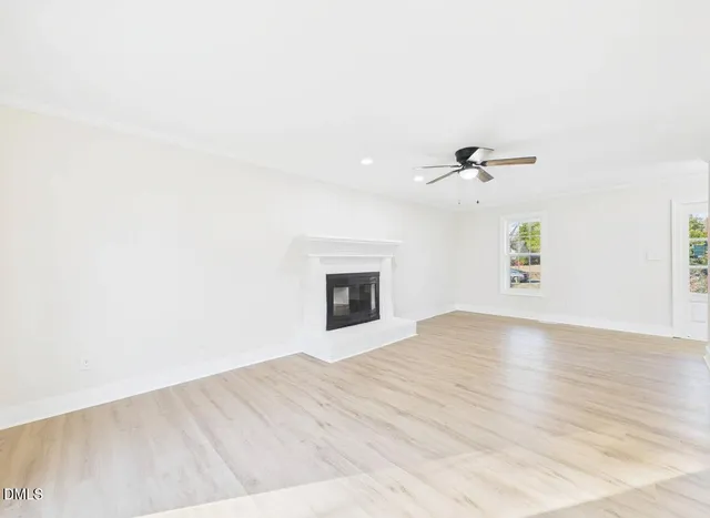a view of an empty room with wooden floor and a ceiling fan