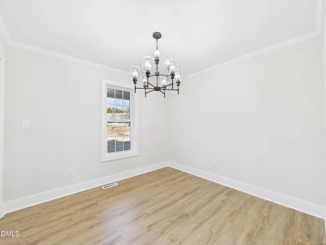 a view of a room with wooden floor chandelier and windows