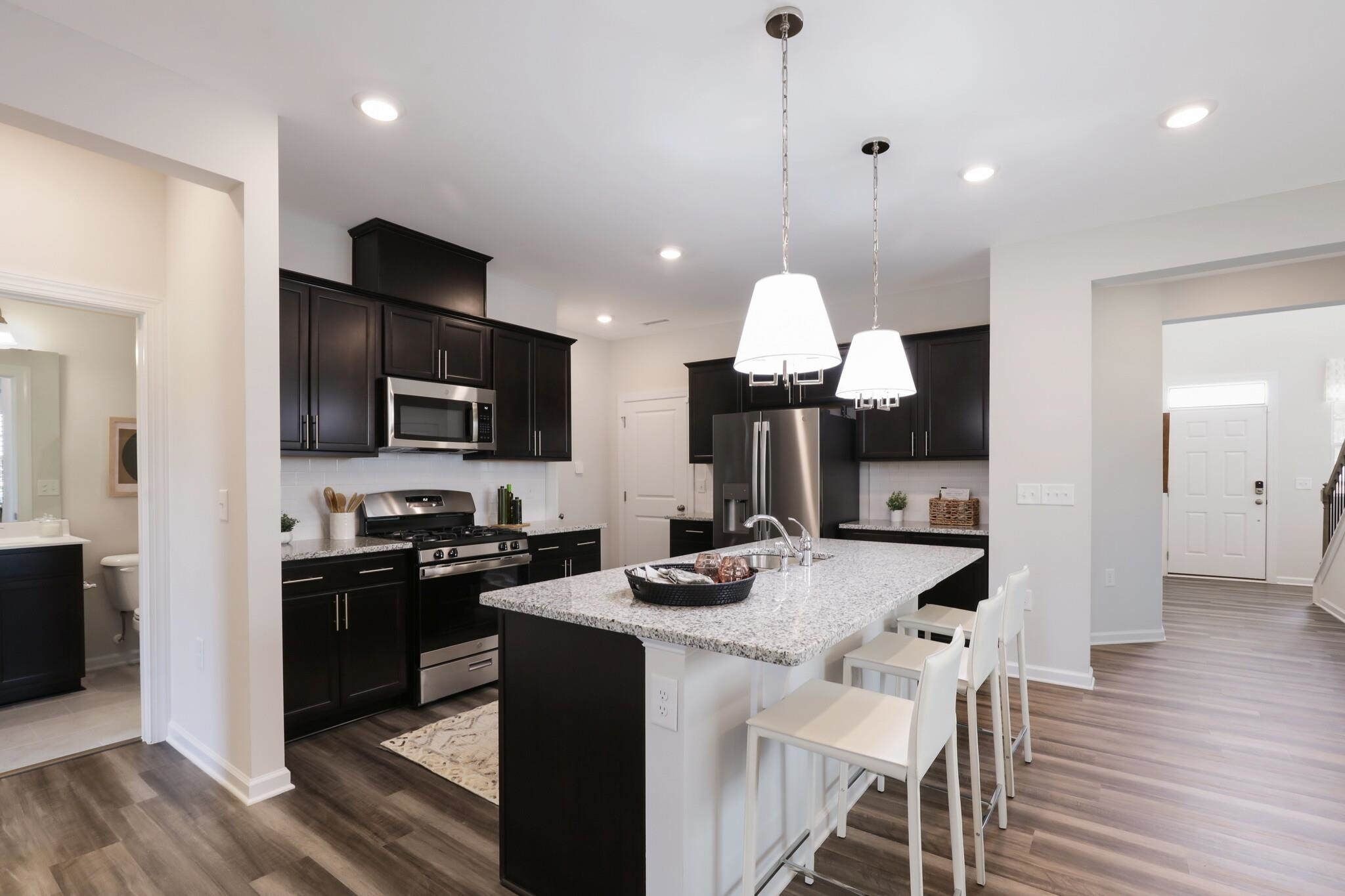 5549 Mill Dam Road, Unit 159 Wake Forest, NC 27587 - Photo 4 of 27 a kitchen with stainless steel appliances kitchen island granite countertop a stove a sink a refrigerator and a microwave