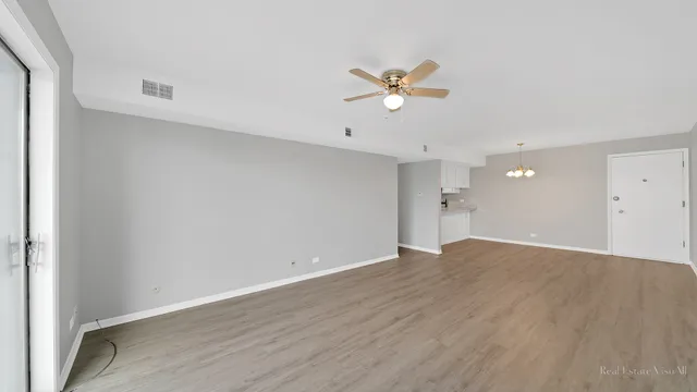 a view of empty room with wooden floor and ceiling fan