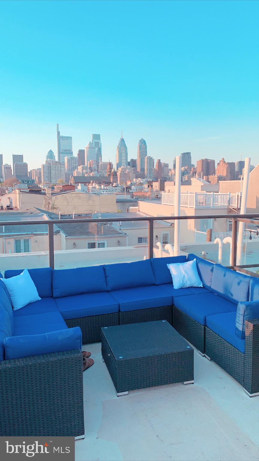 a view of roof deck with furniture and city view
