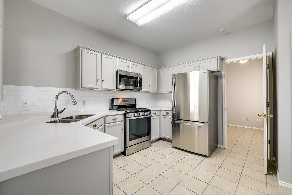 1504 East 19th Street Georgetown, TX 78626 - Photo 4 of 27 a kitchen with a refrigerator sink and white cabinets