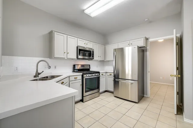 a kitchen with a refrigerator sink and white cabinets