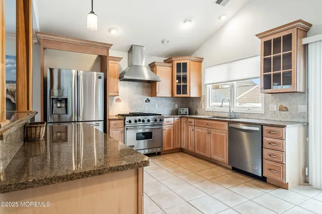 a kitchen with stainless steel appliances a stove a sink a oven a dining table cabinets and chandelier