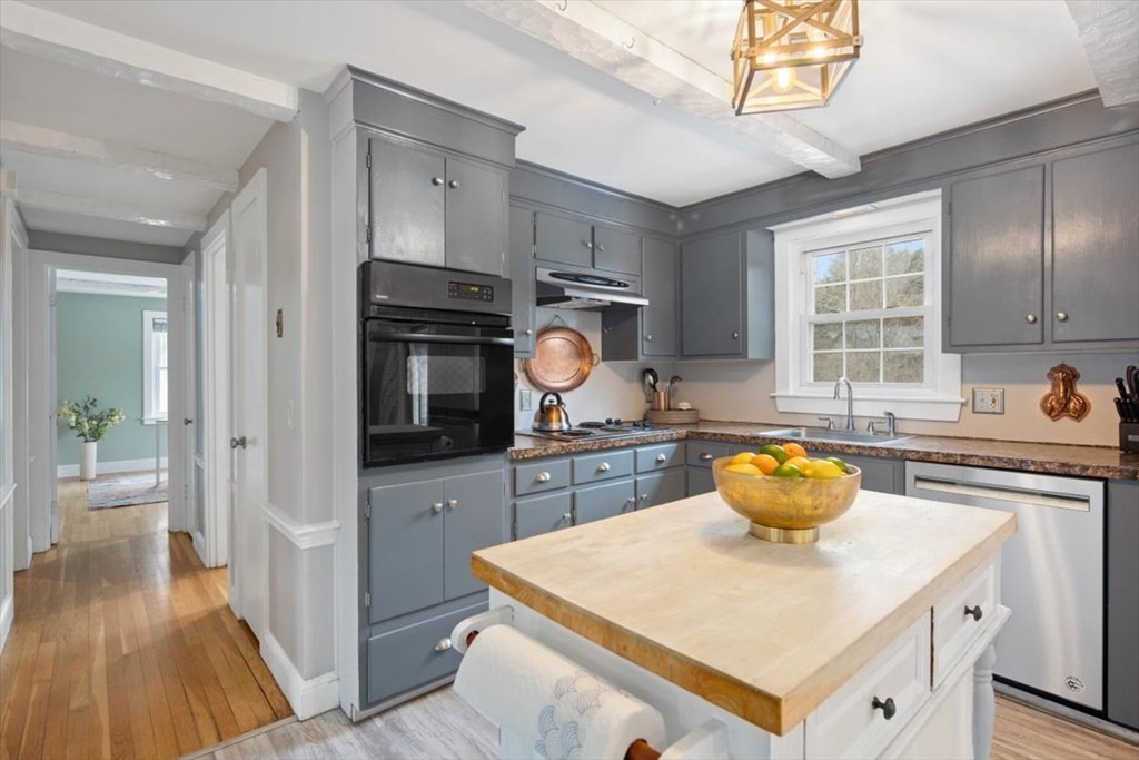 53 Winter Street Kingston, MA 02364 - Photo 11 of 28 a kitchen with stainless steel appliances a stove a sink dishwasher and white cabinets with wooden floor