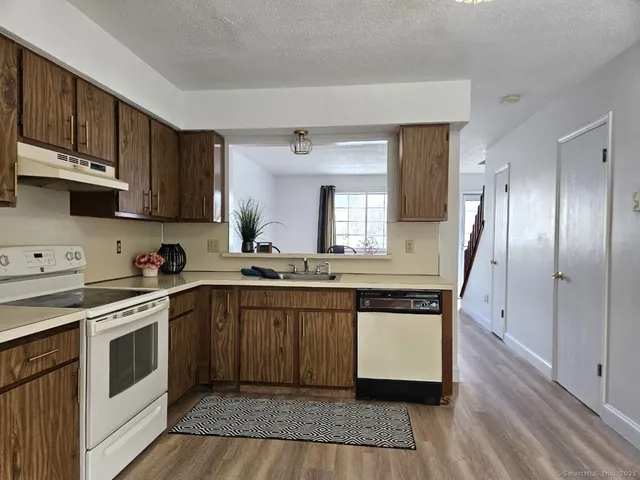a kitchen with stainless steel appliances granite countertop a stove a sink dishwasher and a refrigerator with wooden floor