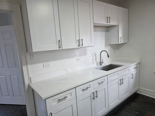 a kitchen with white cabinets and sink