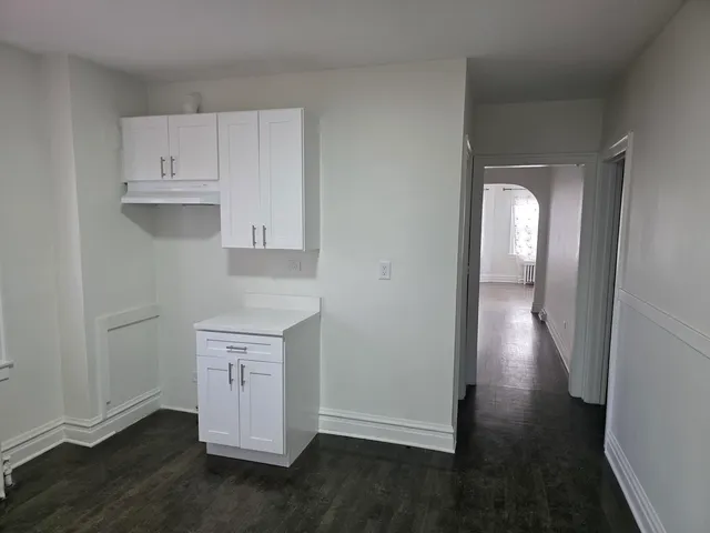 an entryway space with wooden floor and cabinets