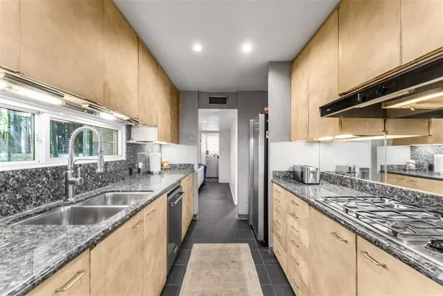 a kitchen with stainless steel appliances granite countertop a sink a stove and a refrigerator